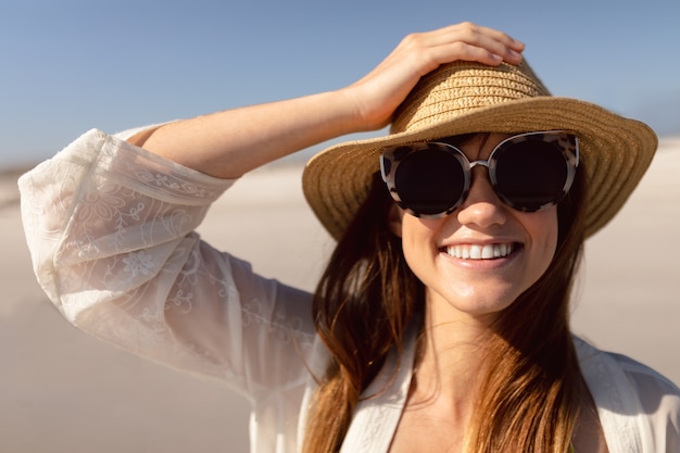 Mujer con sombrero y gafas de sol en la playa